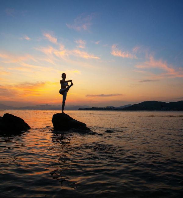 Silhouette of a person in a powerful yoga pose against a sunrise.